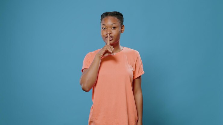 Photo portrait de femme faisant un geste chut avec le doigt sur la bouche, ayant des informations confidentielles privées. jeune personne faisant le symbole du secret et du silence devant la caméra. sujet interdit