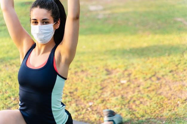 Portrait d'une femme faisant une pose de yoga dans un parc tout en portant un masque. Nouveau concept de normalité