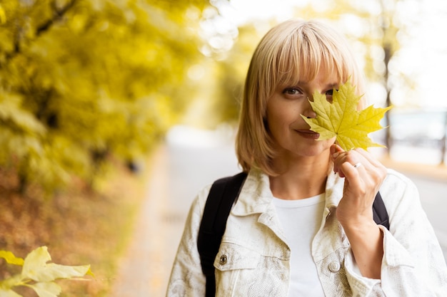 Portrait de femme avec la feuille d'érable jaune d'automne près