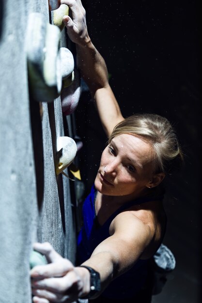 Portrait de femme fit l'escalade à l'intérieur de la salle de gym.