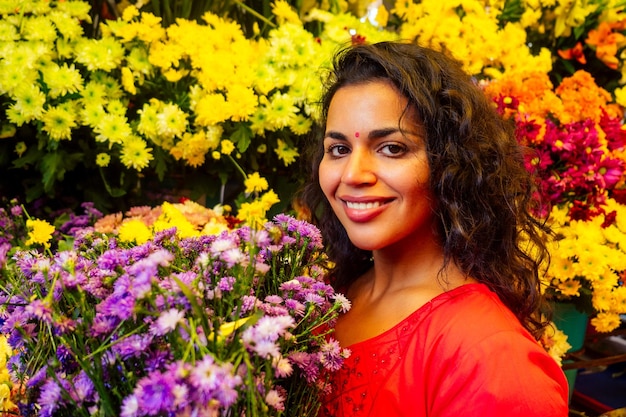 Portrait de femme fleuriste indienne brune dans un bazar floral regardant la caméra et souriant