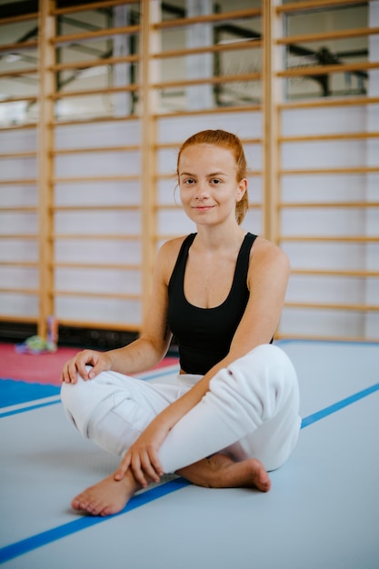 Portrait d'une femme en forme assise sur un tapis de sécurité dans une position assise turque gymnastique