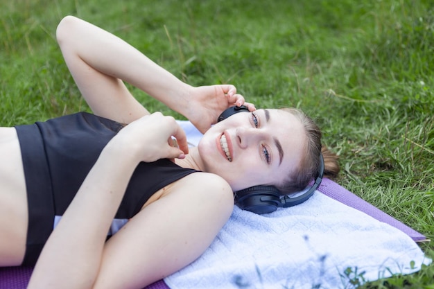 Portrait d'une femme en forme joyeuse allongée sur un tapis dans le parc