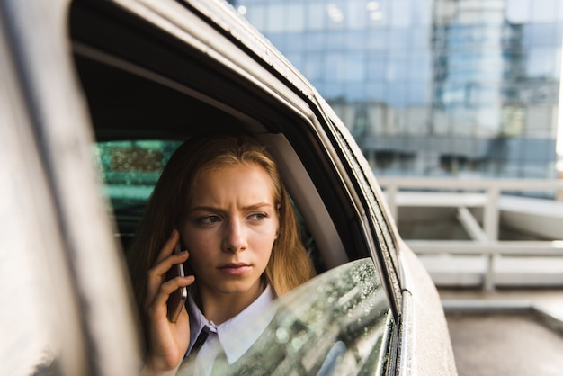 Portrait de femme froncer les sourcils en voiture avec mobile