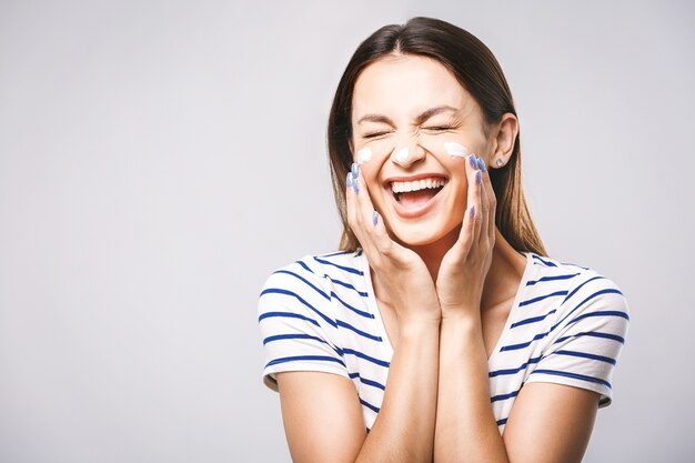 Portrait d'une femme gaie, appliquer la crème pour le visage