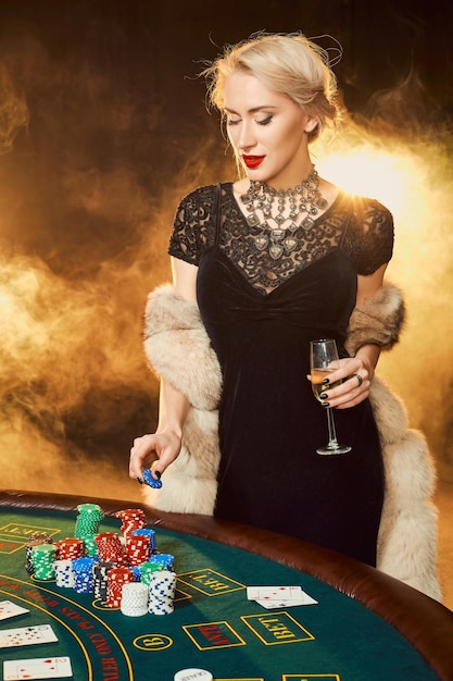 Portrait de femme gardant des jetons de poker près de la table au casino