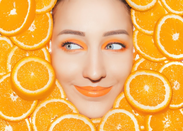 Portrait de femme avec gros plan d'oranges. Maquillage orange vif