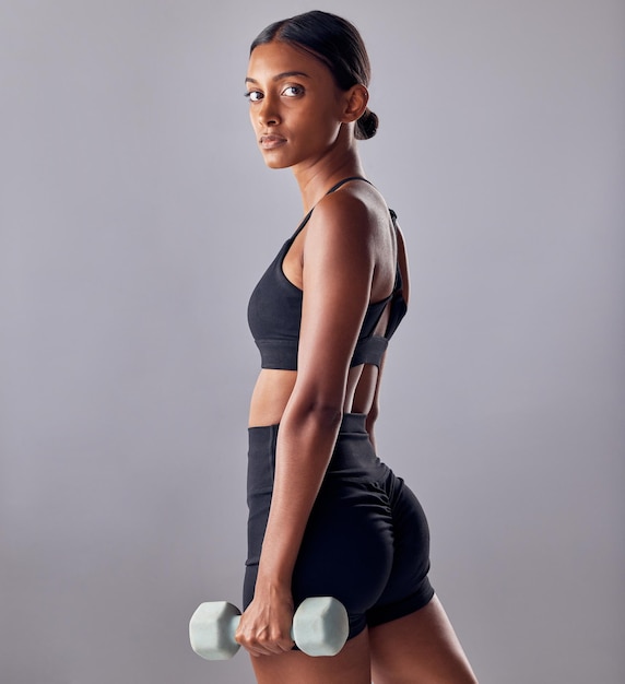 Portrait de femme et haltère en studio pour une forte puissance de bien-être corporel ou des objectifs d'entraînement sains Bodybuildeuse indienne et poids de l'entraînement physique et de l'énergie musculaire dans l'exercice sportif