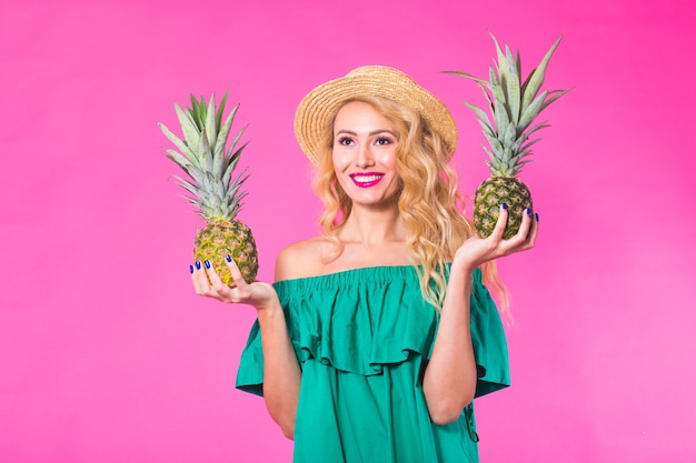 Portrait de femme heureuse et ananas sur mur rose.