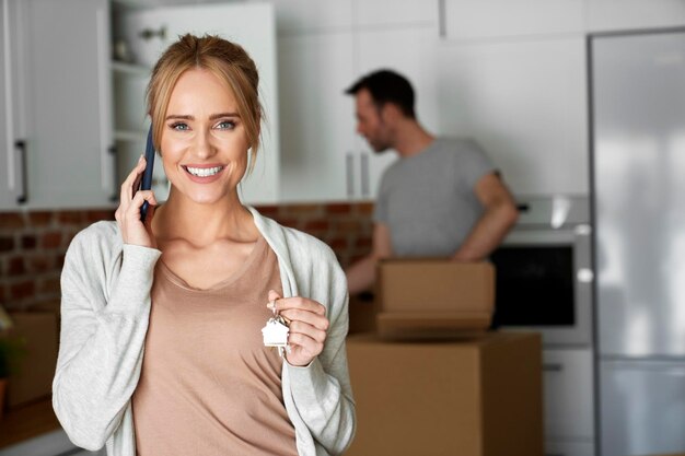 Portrait d'une femme heureuse appelant et tenant les clés de la maison