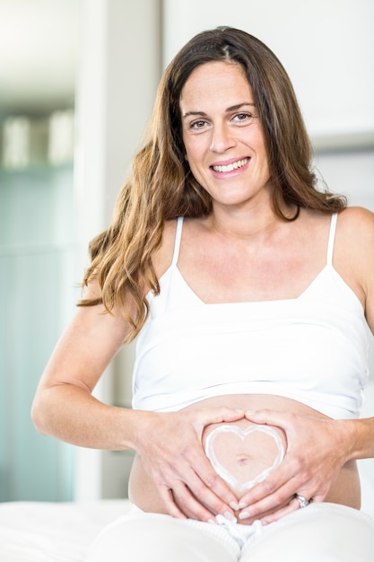 Portrait d&#39;une femme heureuse avec coeur sur le ventre