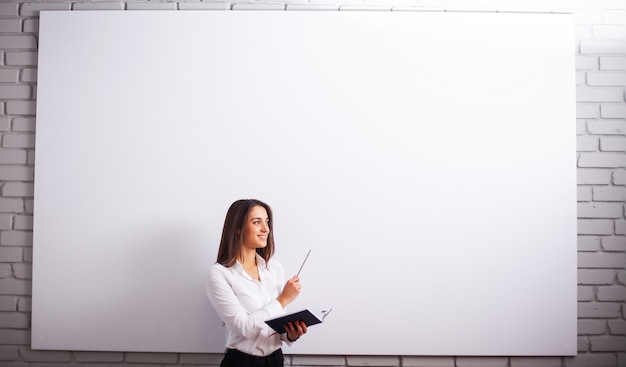 Portrait de femme heureuse jeune femme d&#39;affaires près de mur blanc