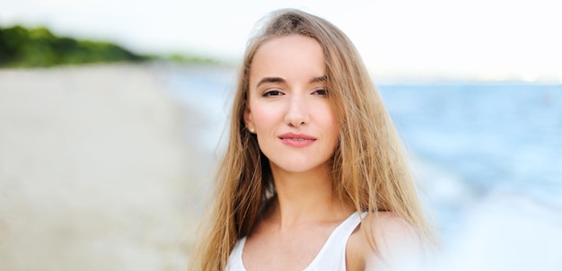 Portrait d'une femme heureuse souriante dans le bonheur libre sur la plage de l'océan profitant de la nature pendant les vacances de voyage à l'extérieur.