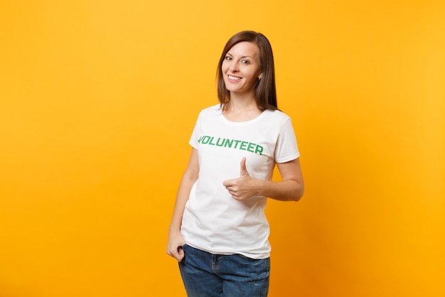 Portrait d'une femme heureuse souriante et satisfaite en t-shirt blanc avec inscription écrite bénévole titre vert isolé sur fond jaune. Aide d'assistance gratuite volontaire, concept de travail de grâce de charité.