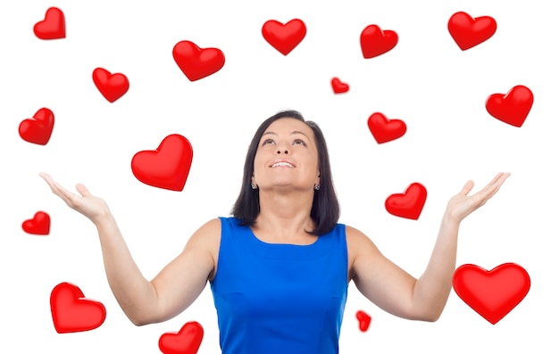 Portrait de femme heureuse sous une pluie de coeurs rouges tombant sur un fond blanc