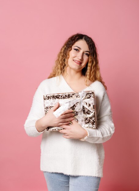 Portrait d'une femme heureuse tenant une boîte-cadeau isolée sur fond rose