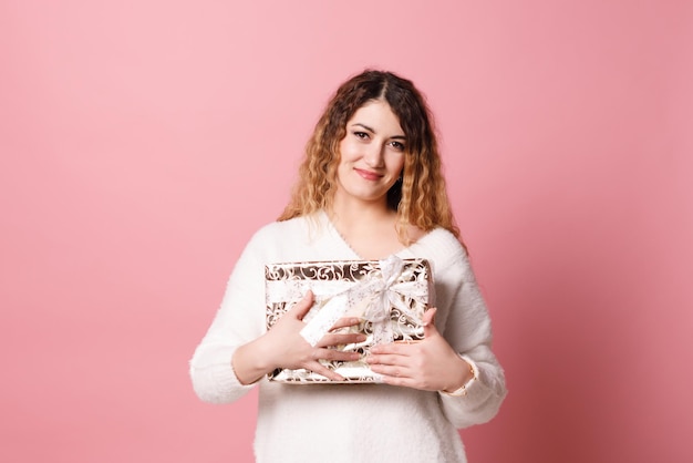 Portrait d'une femme heureuse tenant une boîte-cadeau isolée sur fond rose