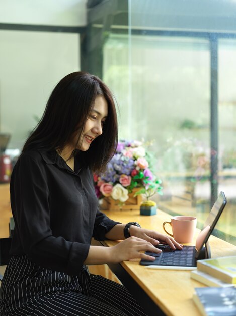 Portrait de femme indépendante à l'aide de tablette numérique avec clavier sur barre de comptoir