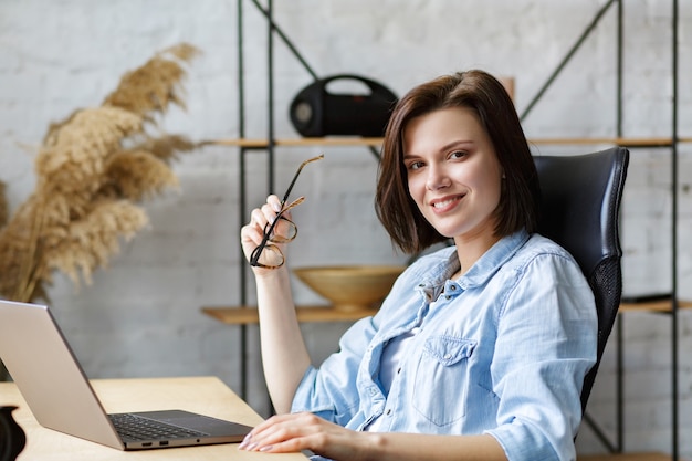 Portrait de femme indépendante souriante à l'aide d'un ordinateur portable.