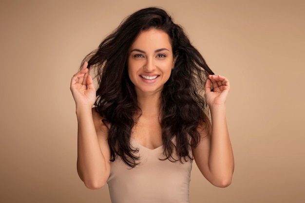 Photo portrait d'une femme indienne souriante touchant de beaux cheveux longs et foncés