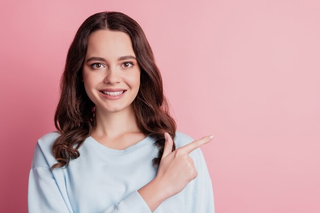 Portrait de femme indiquer doigt montrant sur fond sourire rayonnant sur mur rose