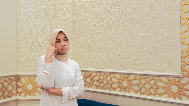 portrait d'une femme indonésienne portant un hijab pensant avec une expression morose bras croisés avec un