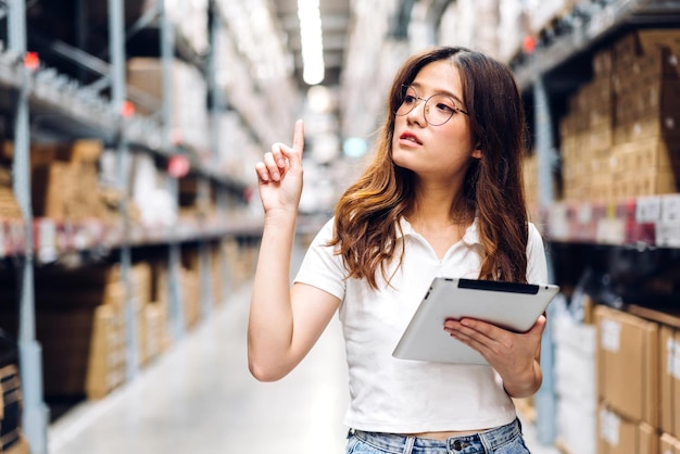 Portrait femme ingénieur asiatique détail de la commande d'expédition sur tablette vérifier les marchandises et les fournitures sur les étagères avec l'inventaire de fond des marchandises dans l'industrie logistique de l'entrepôt d'usine et l'exportation des entreprises