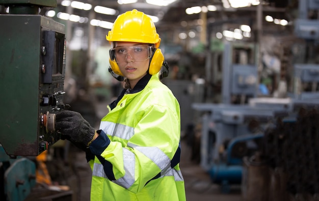 Portrait de femme ingénieur travaillant sur machine cnc debout contre l'environnement de l'usine.