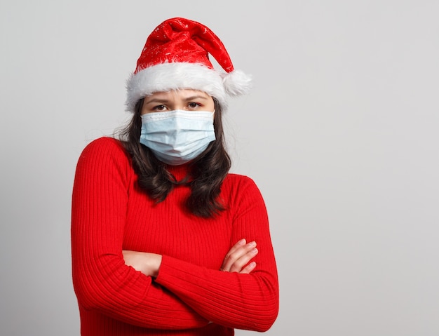 Portrait de femme inquiète portant un masque médical et un chapeau de Noël