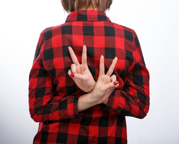 Portrait de femme jeune style décontracté isolé sur fond blanc. Vue de dos. Les mains derrière le dos avec signe de paix.