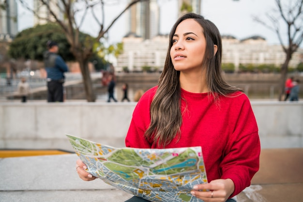 Portrait de femme jeune voyageur tenant une carte et à la recherche de directions à l'extérieur dans la rue. Concept de voyage.