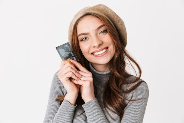 Portrait d'une femme joyeuse des années 30 portant un chapeau tenant un passeport et des billets de voyage isolés sur blanc