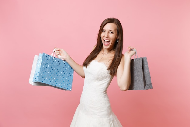 Portrait d'une femme joyeuse excitée en robe blanche en dentelle tenant des sacs de paquets multicolores avec des achats après le shopping