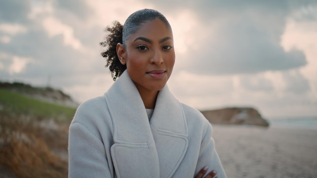 Portrait d'une femme joyeuse se reposant sur la plage d'automne, une afro-américaine heureuse posant.