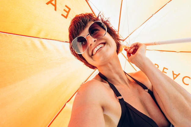 Photo portrait d'une femme joyeuse sous un parapluie ensoleillé