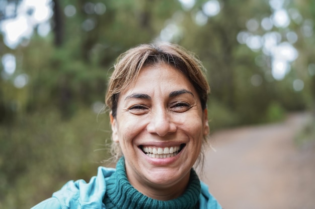 Portrait de femme latine s'amusant pendant la journée de trekking dans le bois - Focus on face