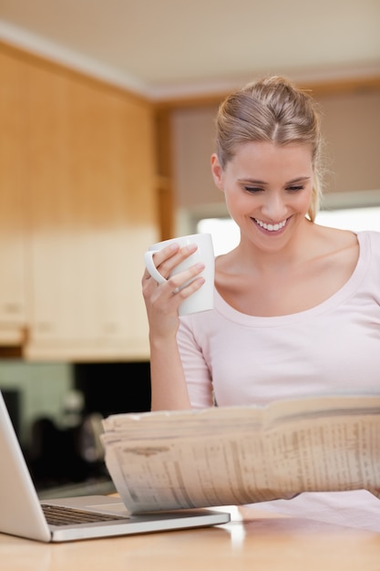 Portrait d&#39;une femme lisant les nouvelles tout en prenant le thé