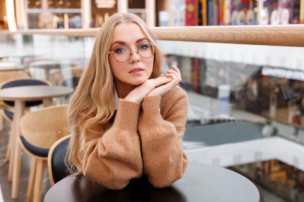 Portrait d'une femme à lunettes et un pull à la cafétéria