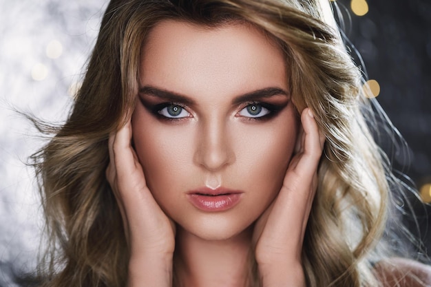 Portrait d'une femme magnifique avec de beaux cheveux bouclés et un maquillage professionnel en studio