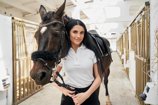 Portrait de femme magnifique caressant son grand cheval de race pure