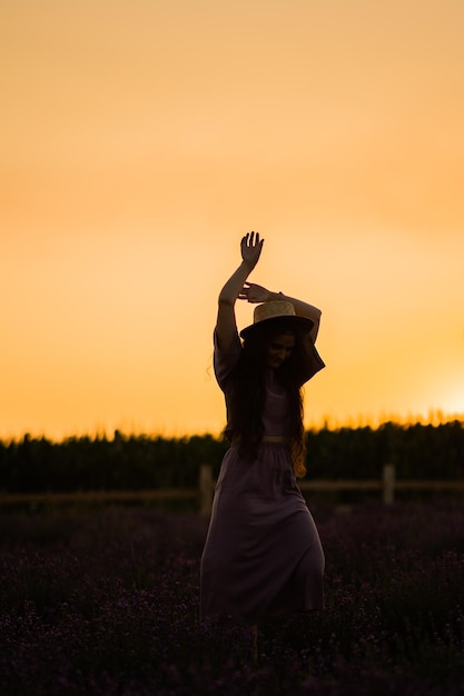 Portrait d'une femme magnifique et élégante marchant sur le terrain posant en regardant le coucher du soleil