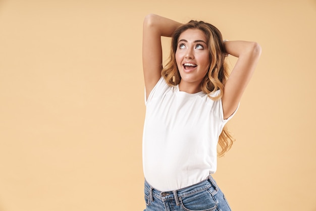 Portrait d'une femme magnifique vêtue de vêtements décontractés souriant et regardant vers le haut au fond isolé