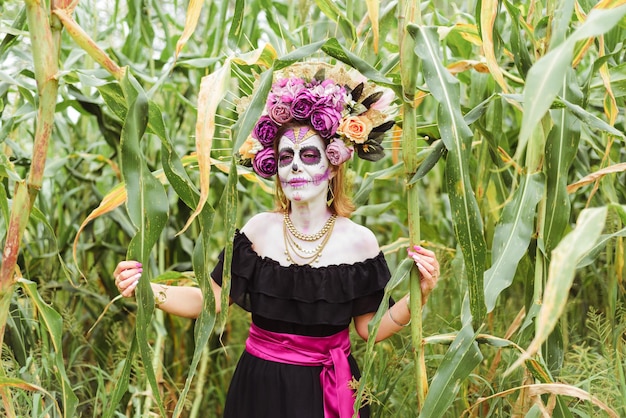 Portrait d'une femme maquillée en catrina dans un champ de maïs.