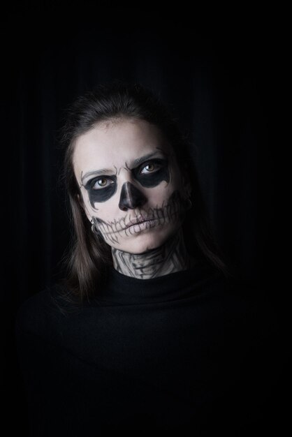 Photo portrait d'une femme maquillée pendant halloween sur un fond noir