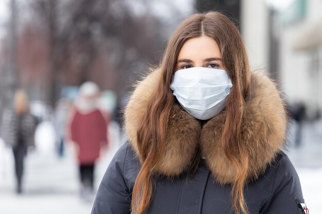 Portrait de femme marchant dans la rue en hiver dans un masque de protection pour se protéger contre les maladies infectieuses Protection contre le rhume grippe pollution de l'air Concept de santé