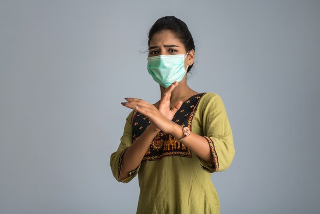 Un portrait de femme avec un masque médical montrant un panneau d'arrêt avec les mains. Concept de soins de santé et de médecine