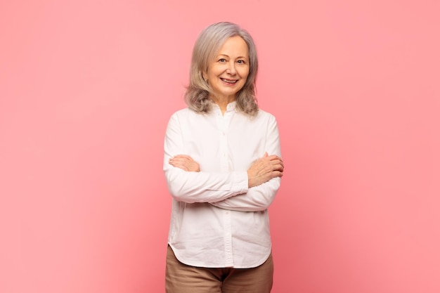 Portrait d'une femme mature aux cheveux gris posant avec les bras croisés