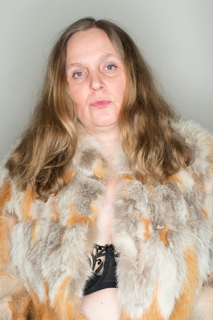 Photo portrait d'une femme mature portant un manteau de fourrure sur un fond gris
