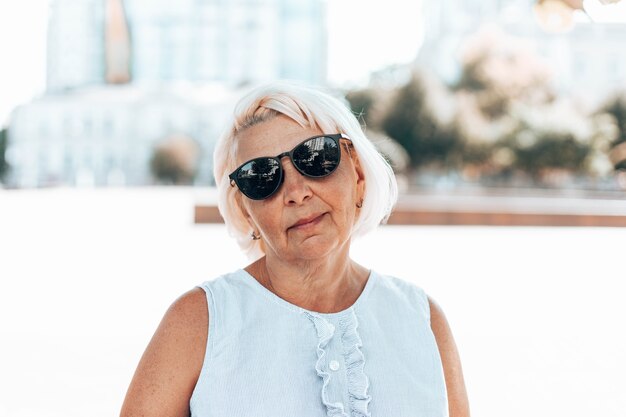 Portrait de femme mature satisfaite positive blonde à lunettes de soleil