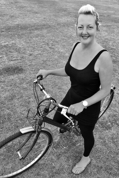 Photo portrait d'une femme mature souriante avec un vélo sur le terrain